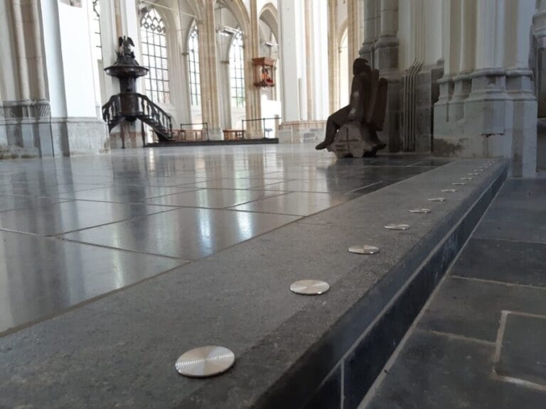 Ronde trapmarkering van metaal op een natuurstenen ondergrond in een kerk.