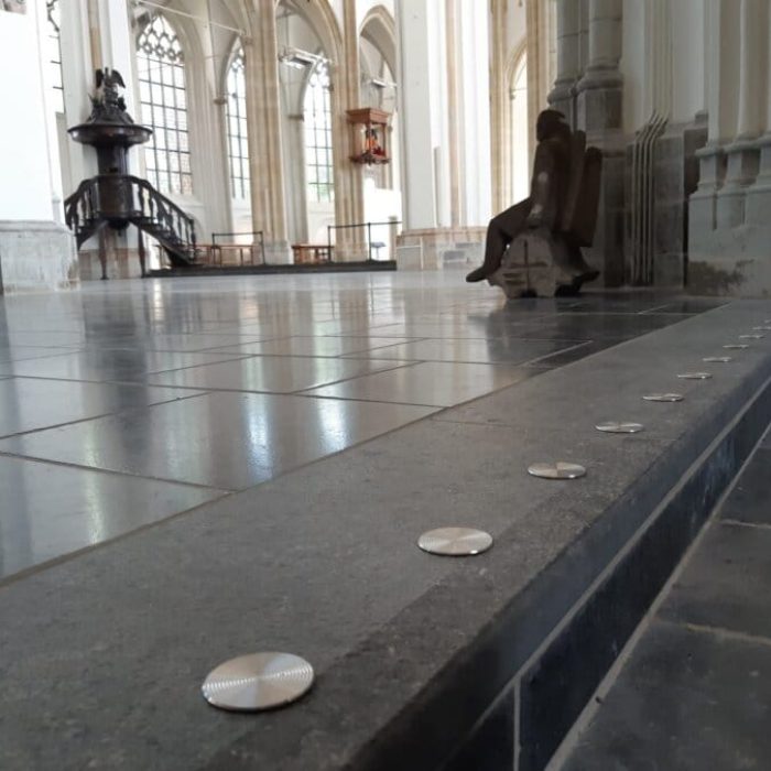 Ronde trapmarkering van metaal op een natuurstenen ondergrond in een kerk.