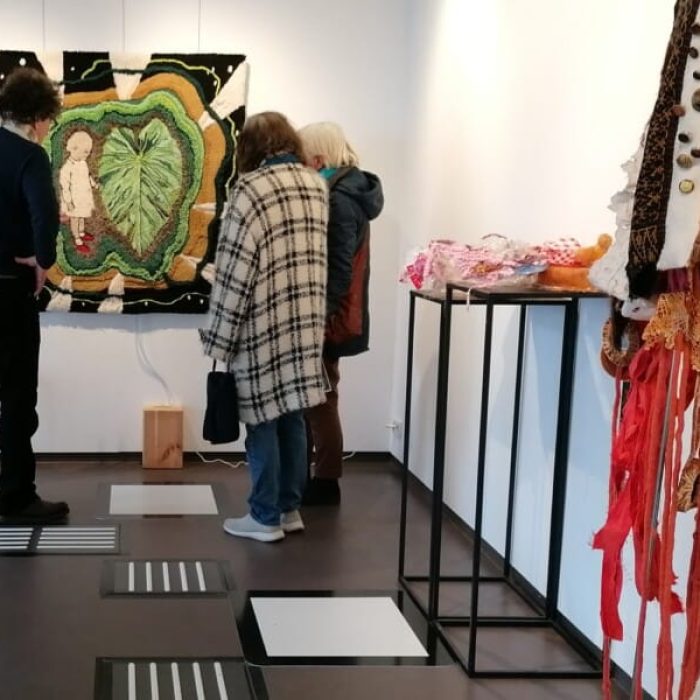 Tijdelijke geleideroute van matten en klankplaten in een expositieruimte met tastbare kunstwerken.