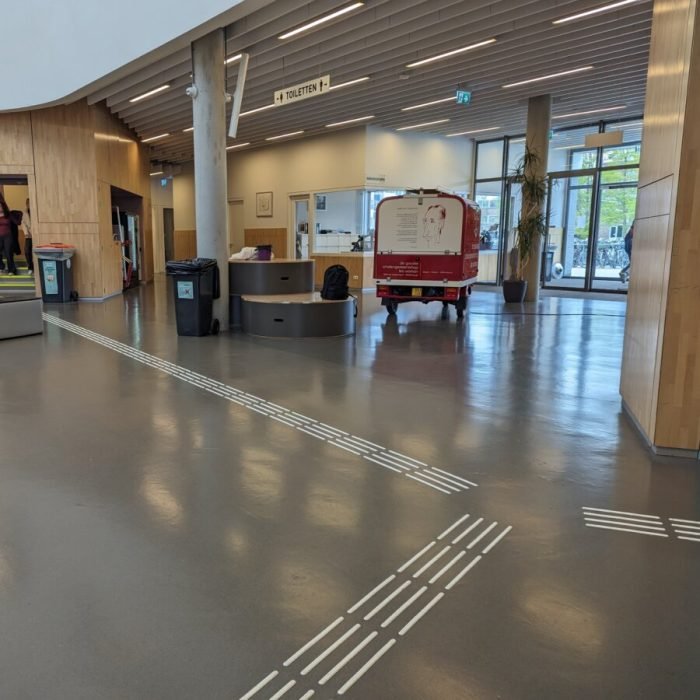 Ribbels in drie richtingen. Er is veel weerspiegeling op de vlakke vloer van de TL-balken aan het plafond.